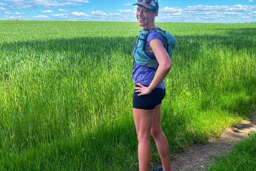 runner standing on a trail looking at a field in Lux
