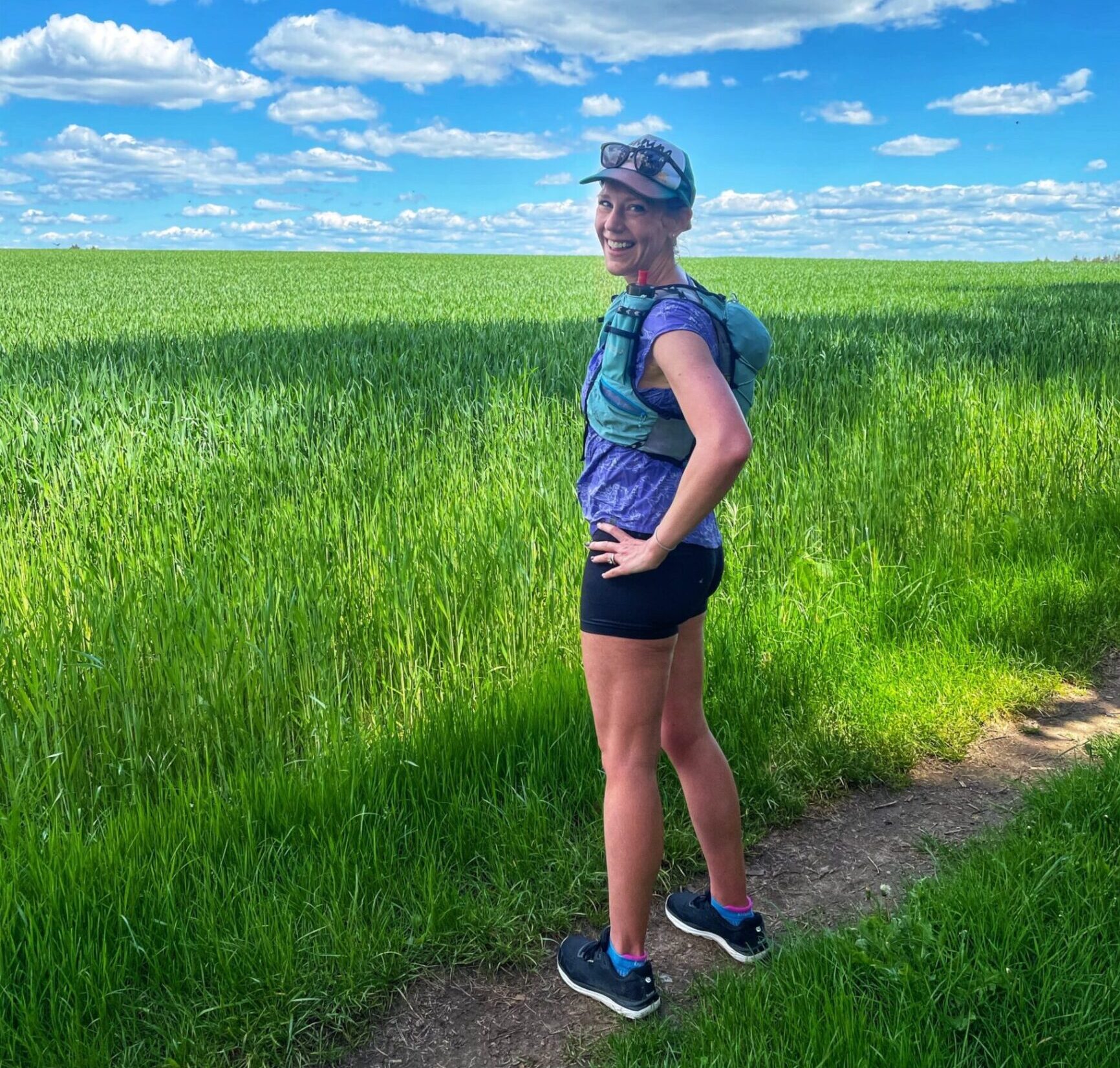 runner standing on a trail looking at a field in Lux